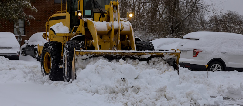 Snow plow clearing office parking lot